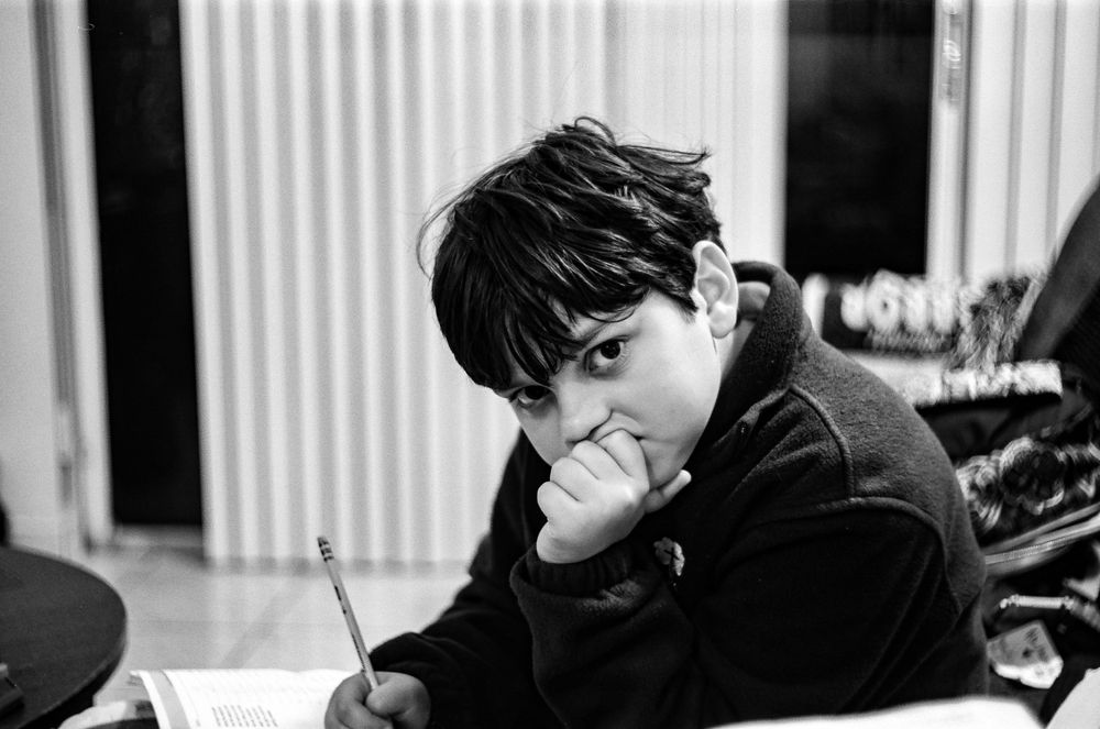 Black and white candid shot of someone writing or studying at a desk.