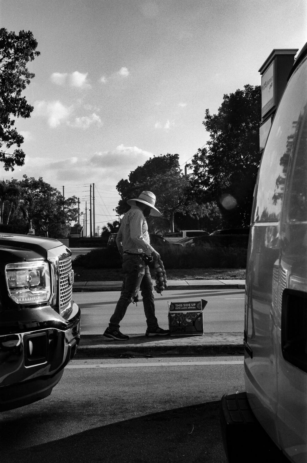 Silhouetted figure working between parked vehicles in dramatic black and white lighting.