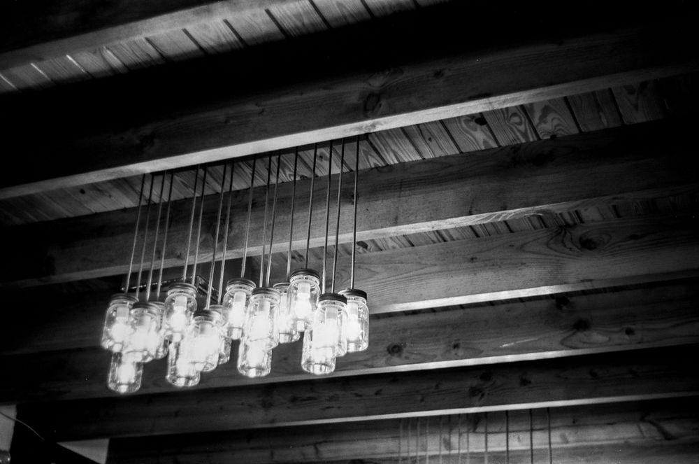 Modern pendant light fixture with hanging glass jars mounted on a wooden ceiling.