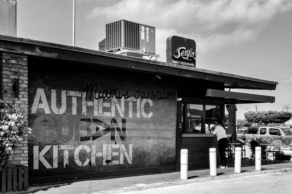 Black and white exterior of restaurant with 'Authentic Kitchen' painted on brick wall.
