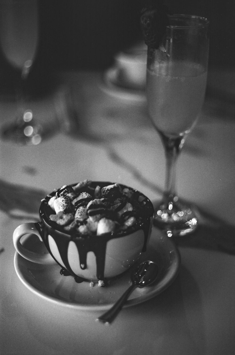 A decadent dessert in a cup with chocolate drizzle served alongside a champagne flute.
