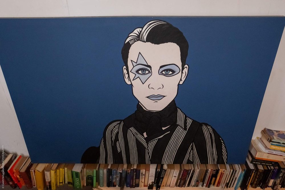 Pop art style illustration shows figure in black turtleneck with decorative markings on face against blue background.