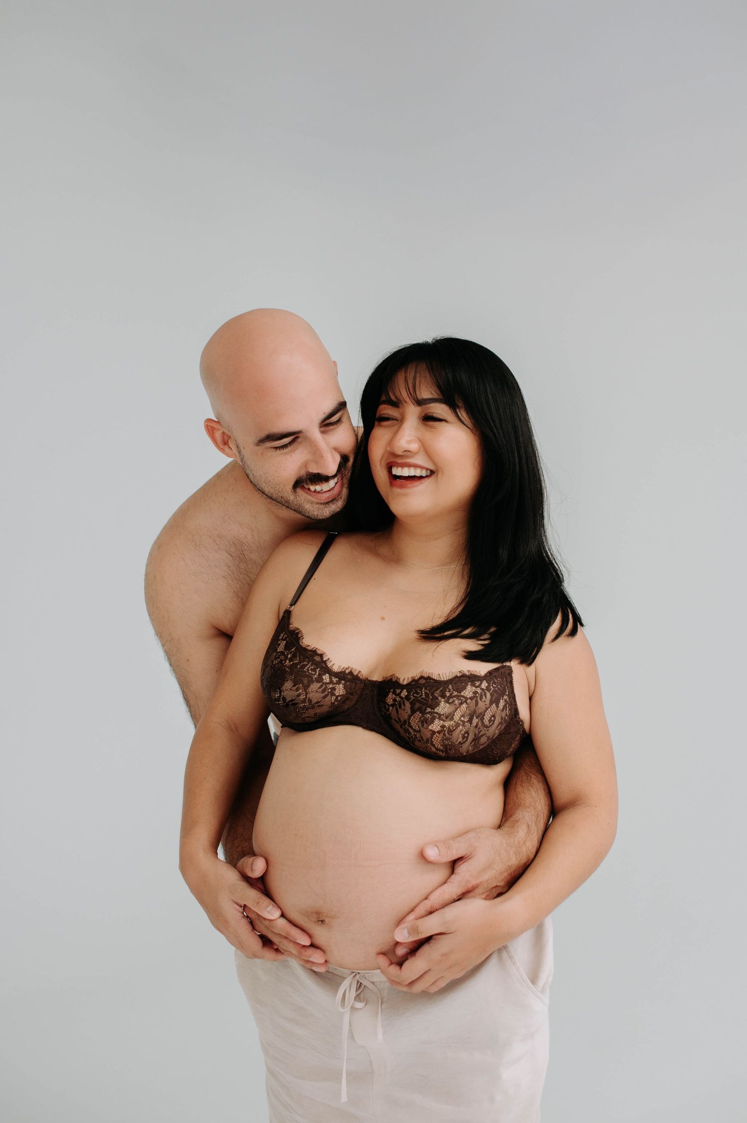 Intimate maternity portrait of expecting couple in minimalist setting.