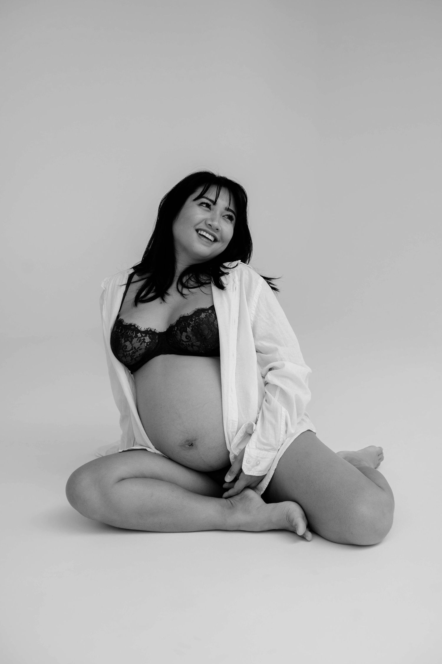 Black and white maternity photo showing expectant mother in relaxed pose.