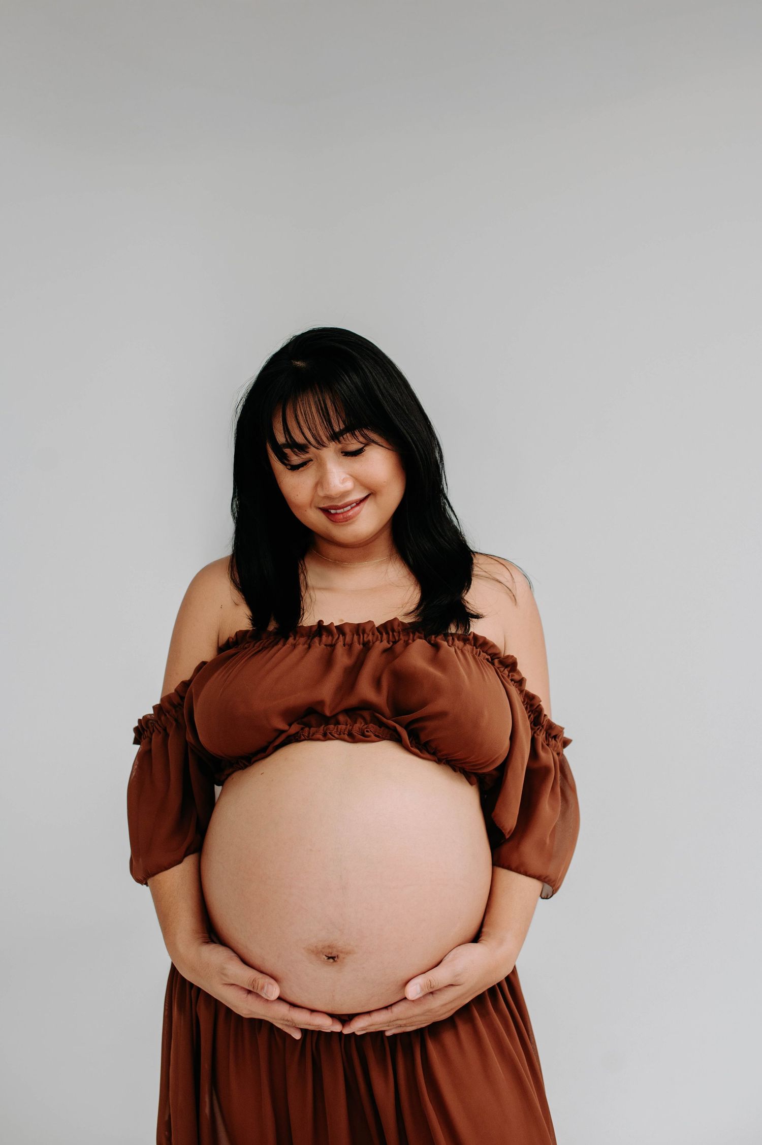 Radiant maternity portrait with woman wearing brown ruffle dress.