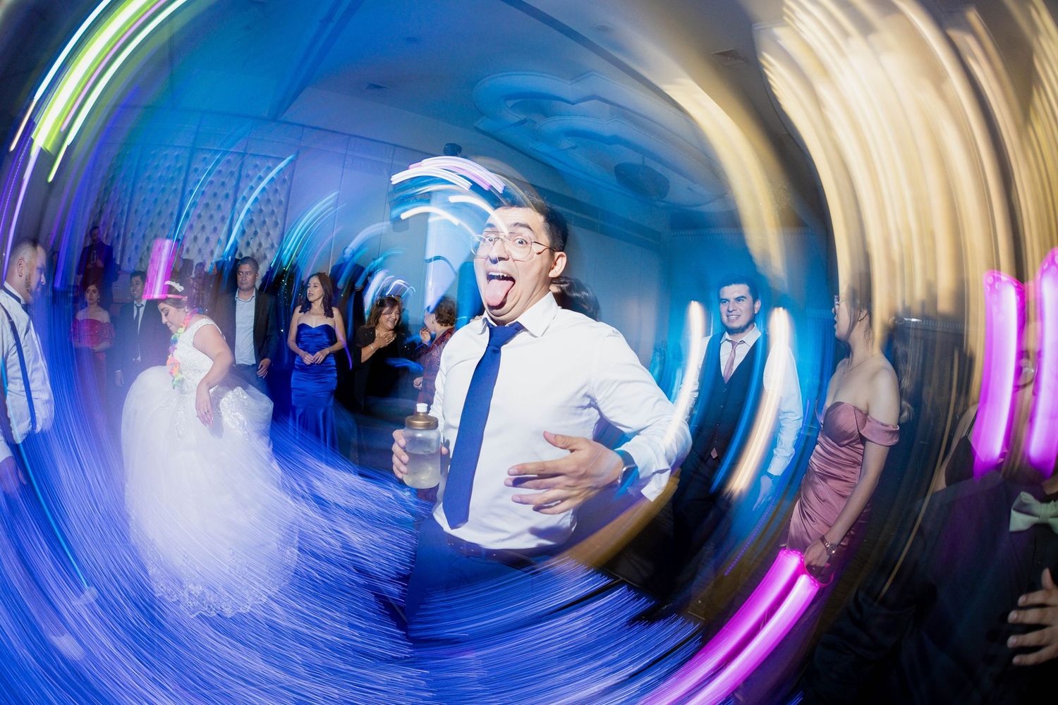 Wedding reception celebration captured in a fisheye lens with vibrant blue and purple lighting effects.
