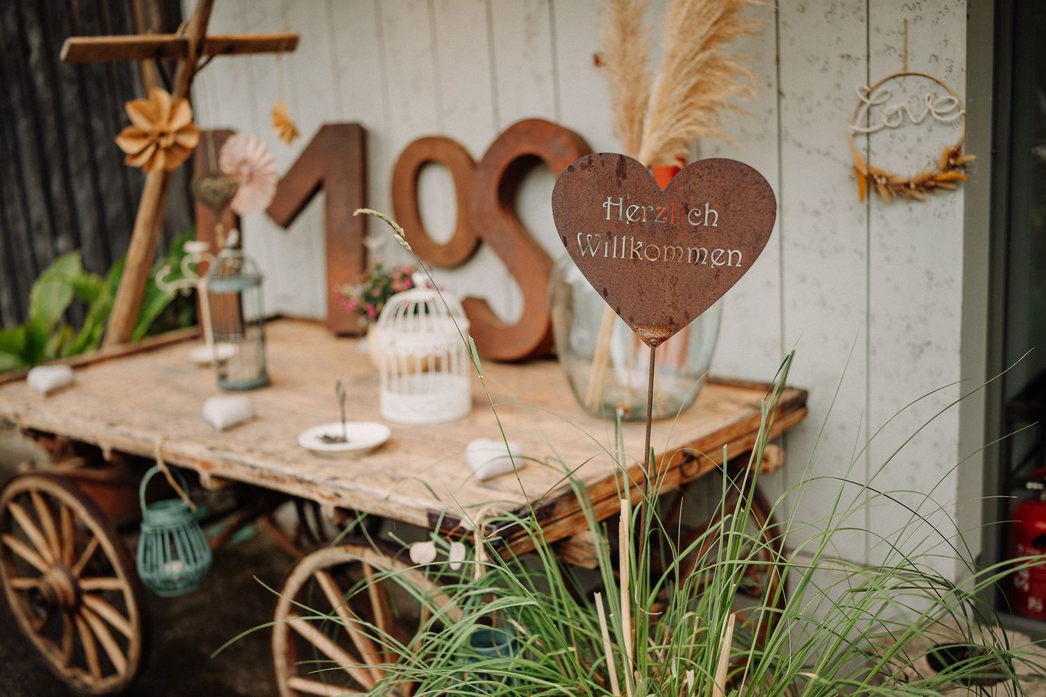 Rustic wedding decor featuring wooden numbers, a metal heart sign, and decorative elements on a vintage cart display.