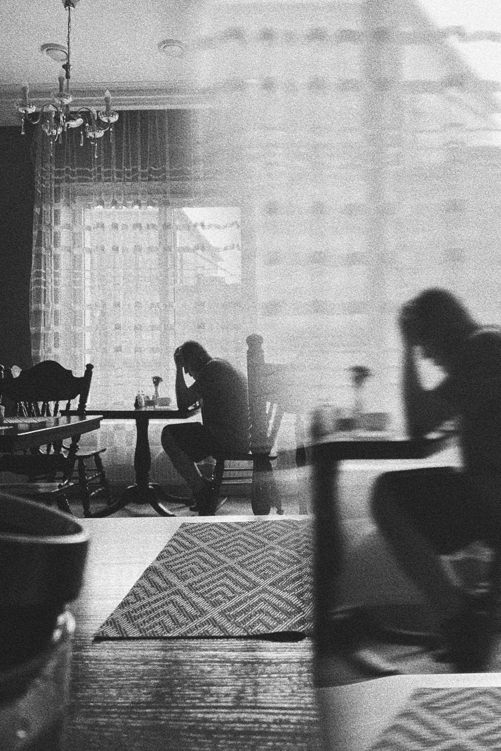 Silhouettes of people sitting in dimly lit cafe with geometric pattern carpet.