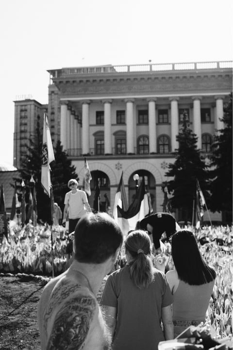 People gathered in front of classical building with tulips blooming in foreground.