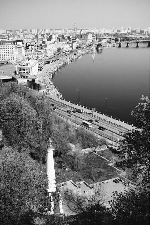 Black and white aerial view of a city waterfront with bridges and buildings along a curved riverbank.