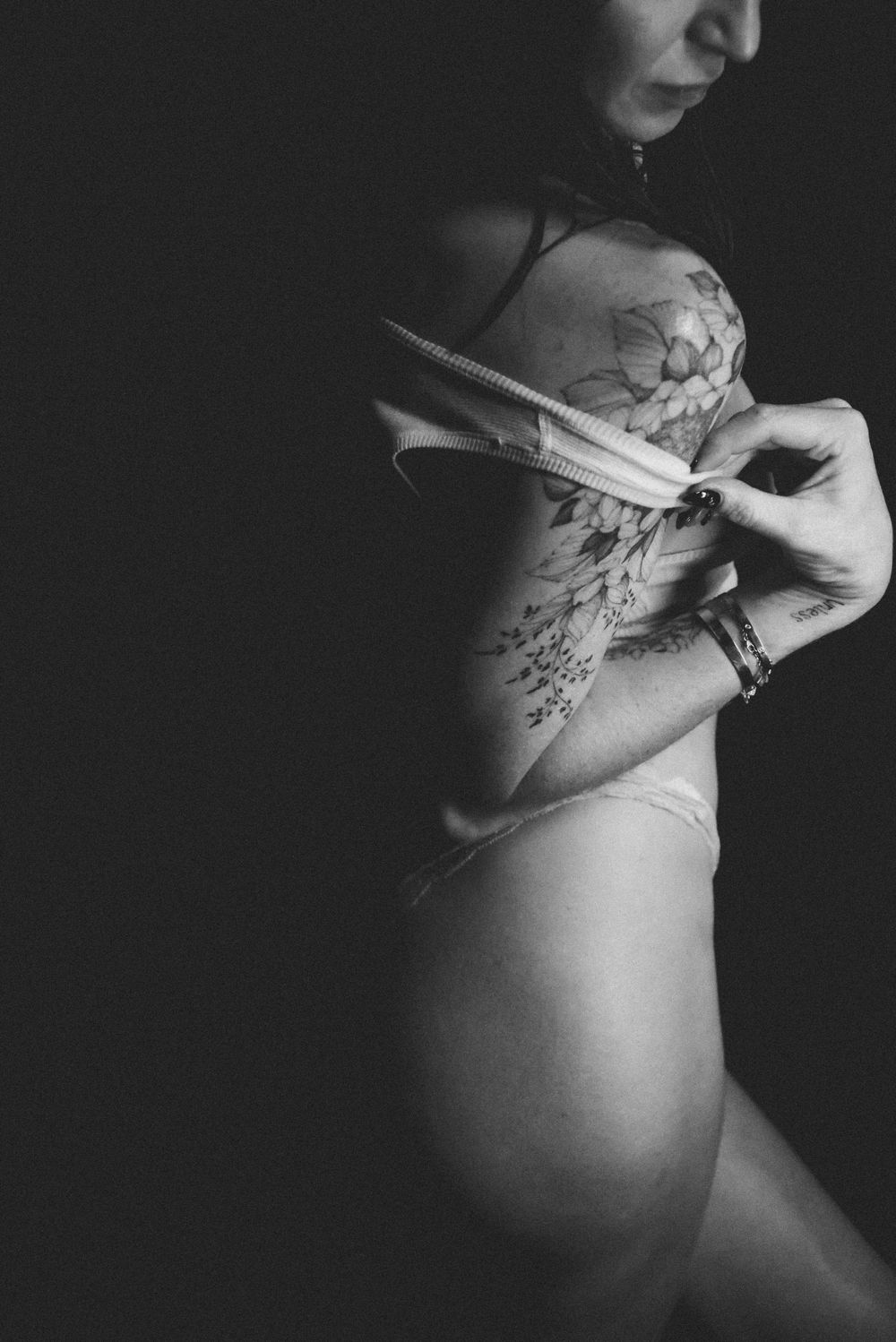 Black and white artistic maternity photo series showing a pregnant belly with floral tattoo art.