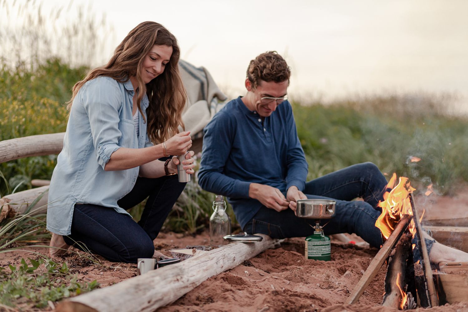 Couple preparing food at a beach campfire during a storytelling couples photoshoot in Chelton,PEI with Lumenali Photography Novella Session.