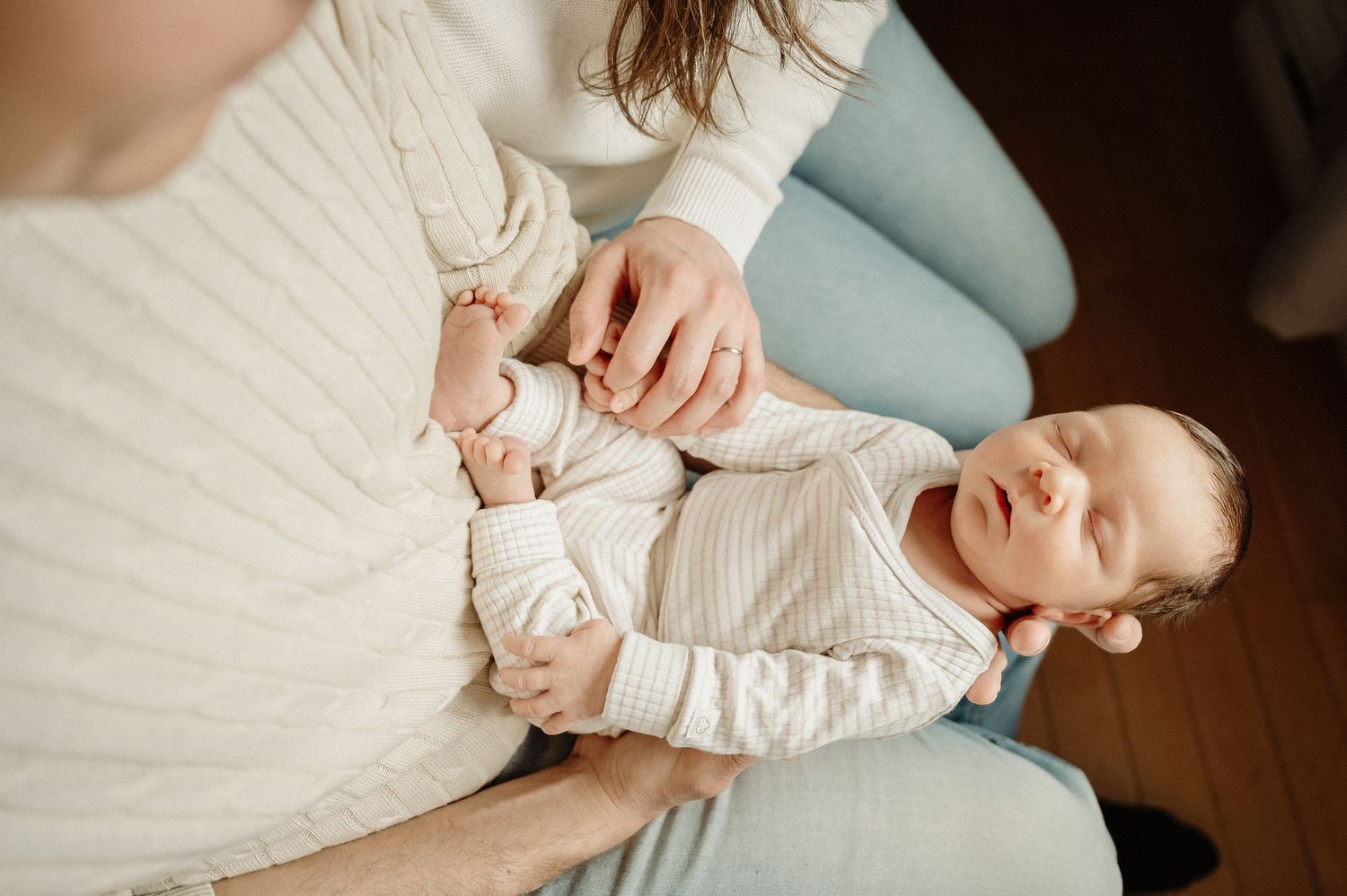 An intimate moment with a newborn baby captured on hardwood floors in natural light.