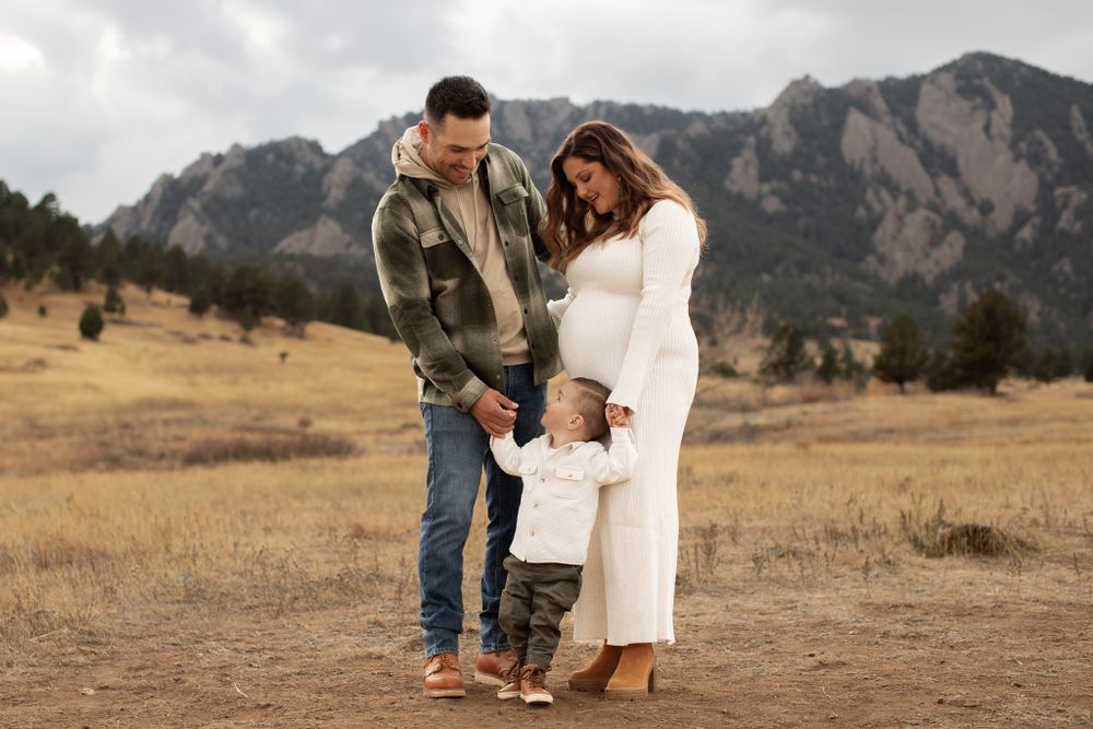A family stands together in an open field with the majestic Flatiron Mountains of Boulder, Colorado in the background.