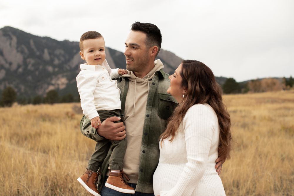 Family enjoying a warm autumn day together in a field with mountains in the background.