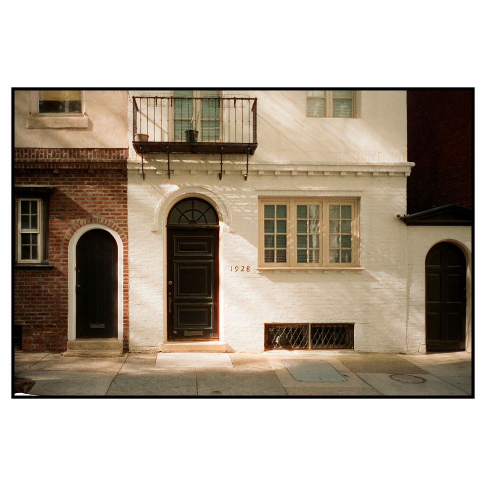 Vintage row house entrances with arched doorways and white painted brick facade along an urban sidewalk.