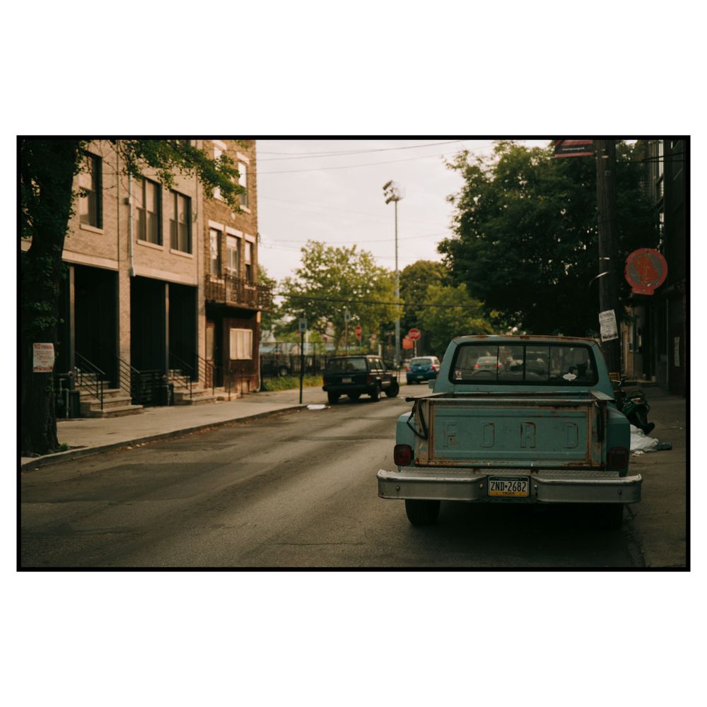 Small town street view with vintage pickup truck parked along storefronts on a sunny day.