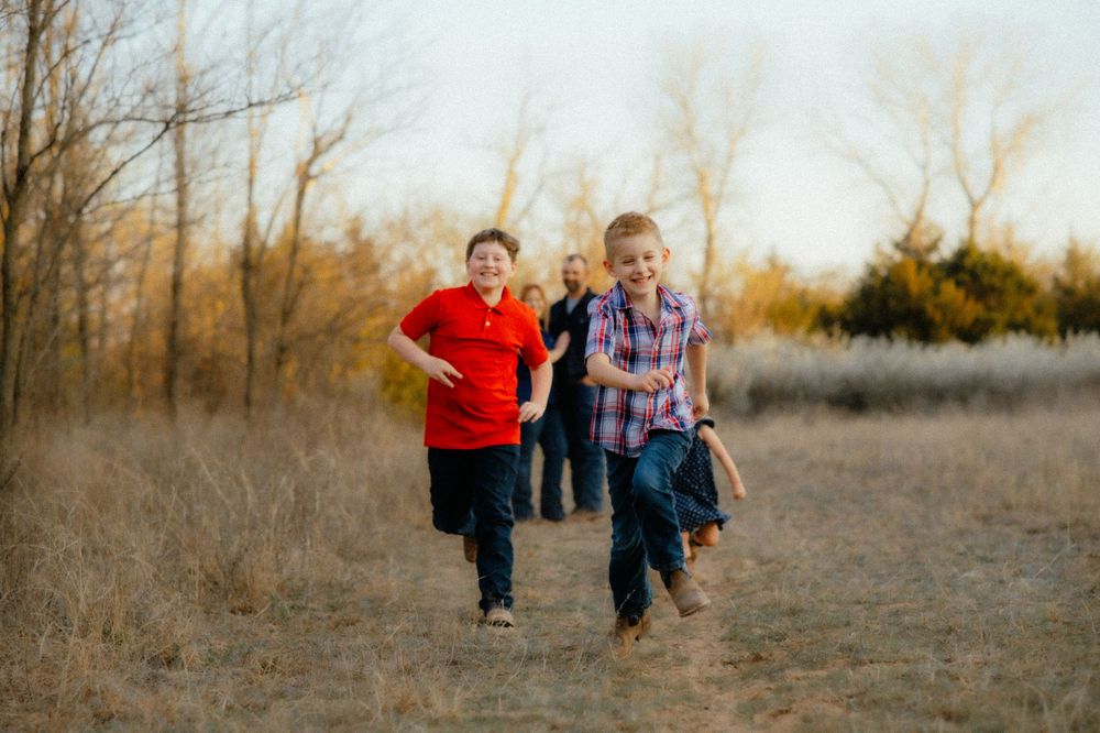 Kids racing while mom and dad smile during family photos near Alva Oklahoma.