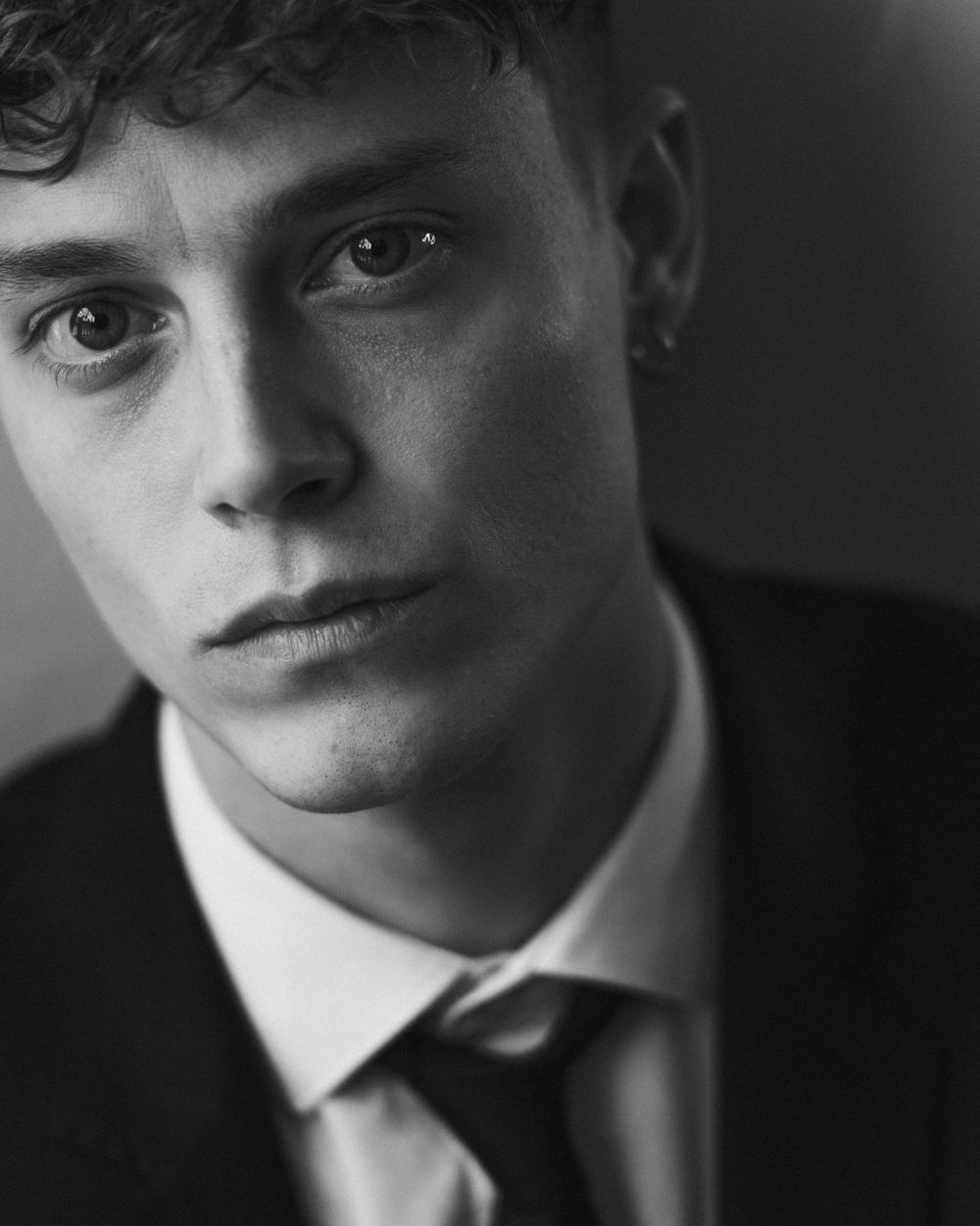 Dramatic black and white closeup portrait of groom in formal attire.