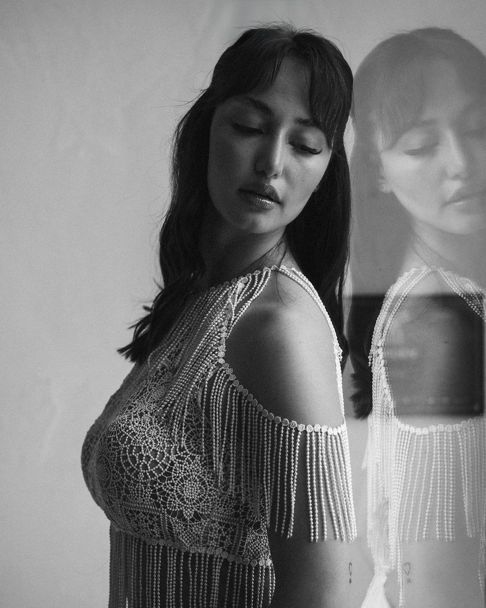 Artistic portrait of woman in beaded gown with reflection creating ethereal double image. Next day wedding photography.