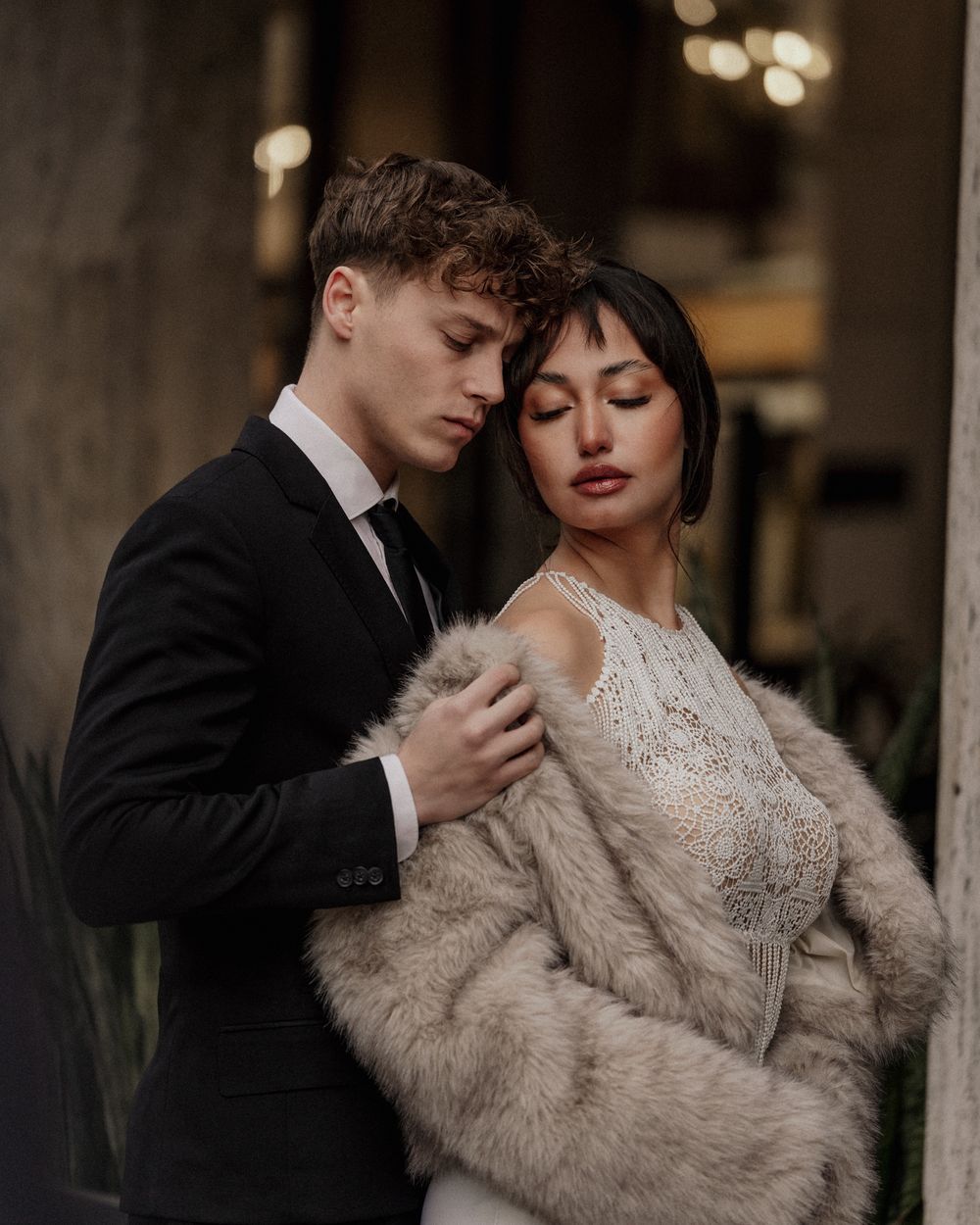 Intimate moment between newlyweds, bride wearing lace dress and fur wrap. Next day wedding photography.