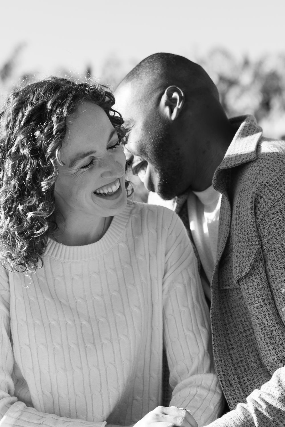 A romantic black and white photo series showing a couple laughing and sharing intimate moments together.