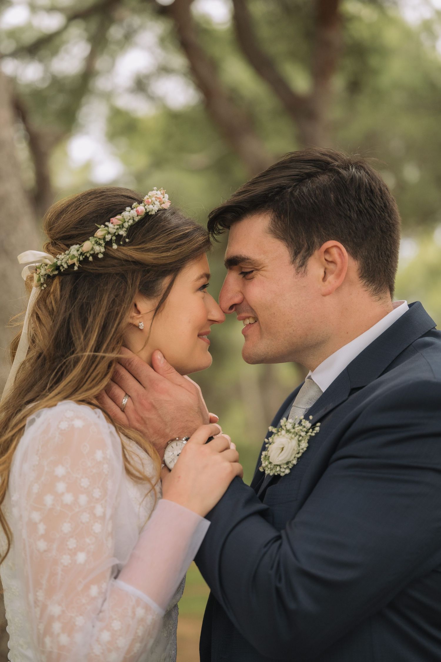 A romantic wedding portrait showing a tender moment between newlyweds in a forest setting.
