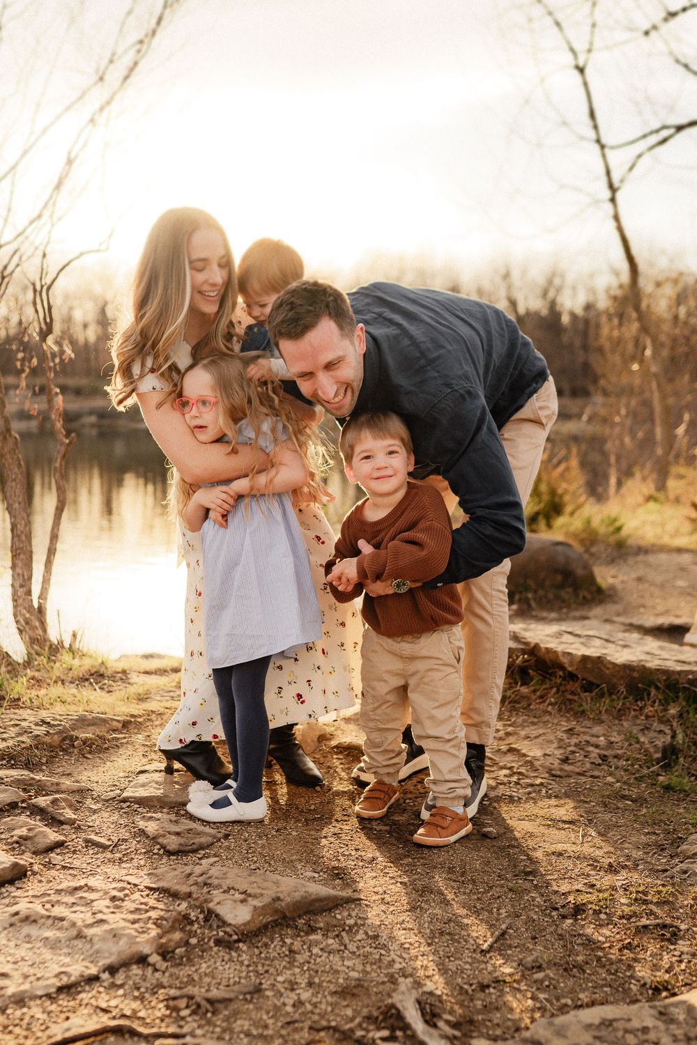 Family enjoying a sunset moment together by a lake on an autumn afternoon.