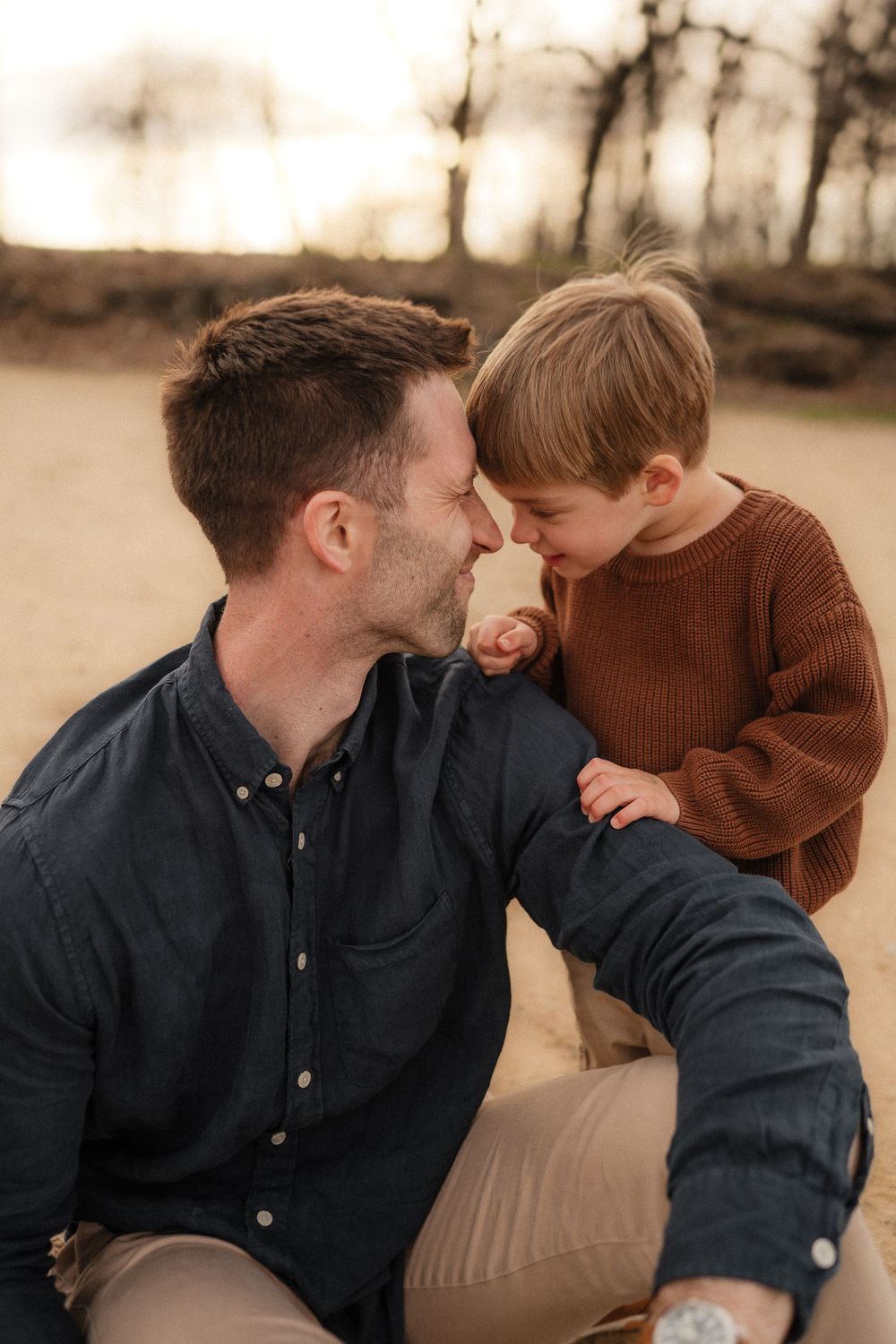 A candid outdoor portrait shows a tender moment between parent and young child in warm sepia tones.