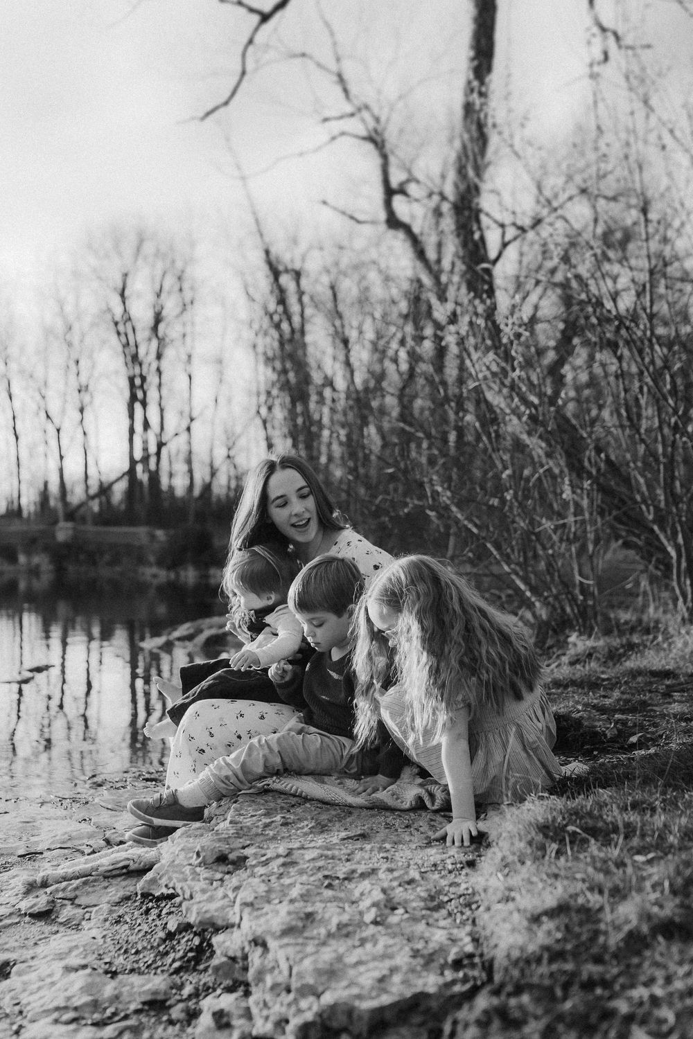 A black and white photo of a relaxing scene by a lake with a dog companion on a calm afternoon.