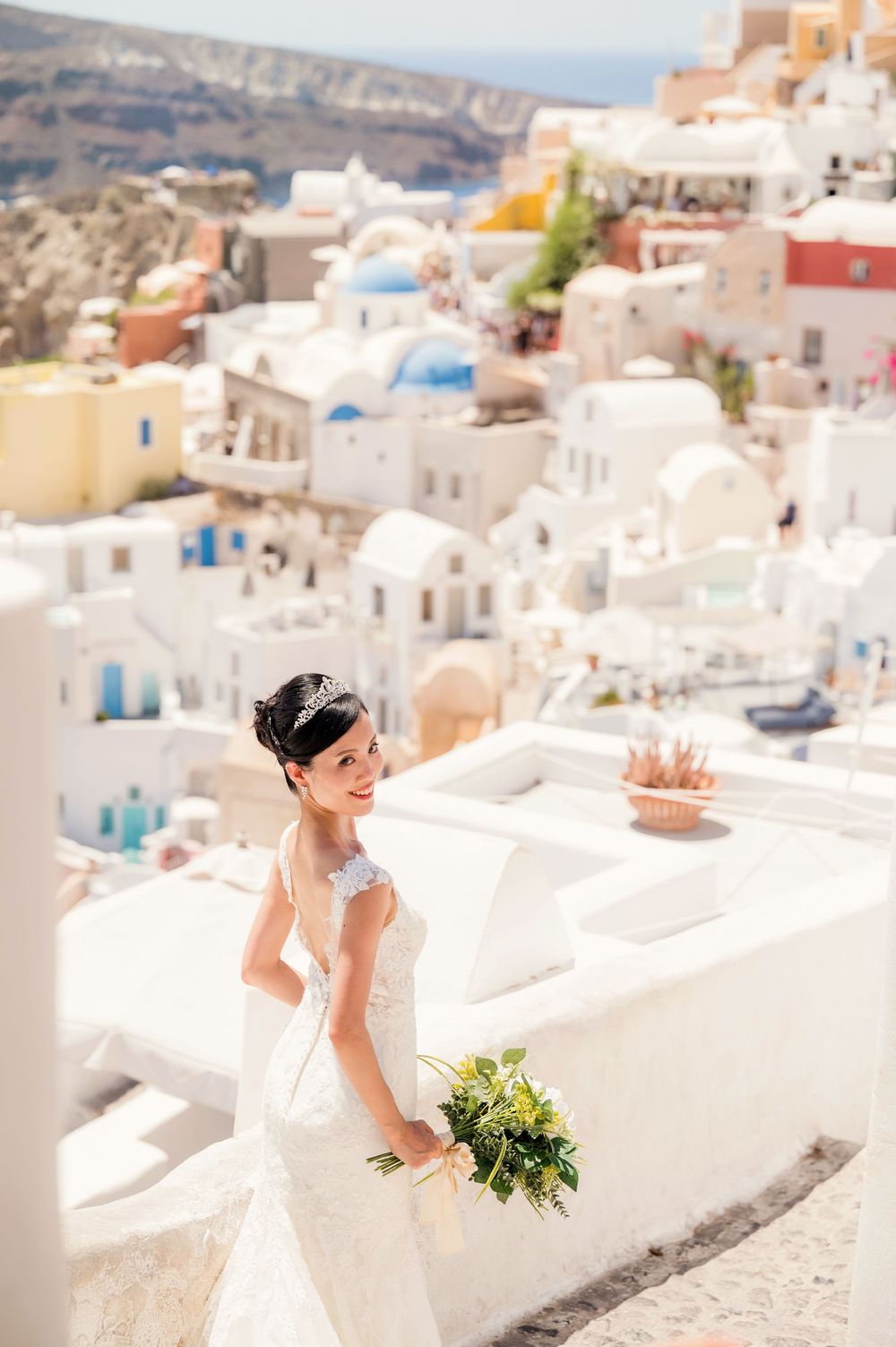 A joyful bridal portrait among the white buildings and blue domes of Santorini's iconic landscape.