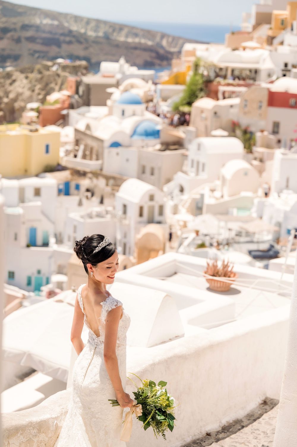 A elegant bridal pose captured against the scenic backdrop of Santorini's white-washed buildings.