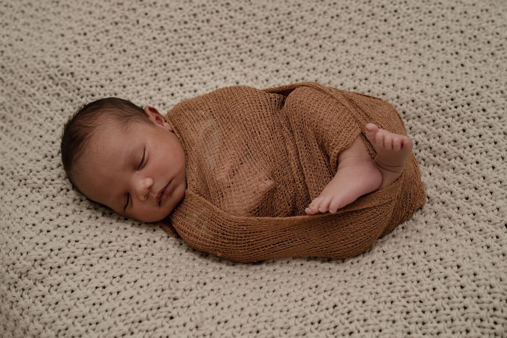 Peaceful sleeping baby on cream knitted blanket in soft natural light.
