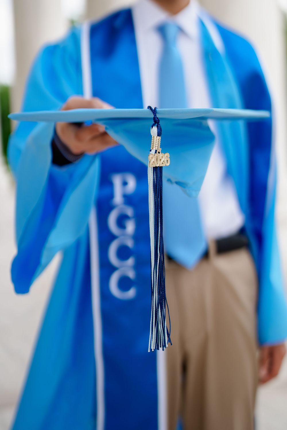 PGCC graduate in blue cap and gown holds mortarboard with 2020 tassel outdoors at the Jefferson memorial in Washington DC