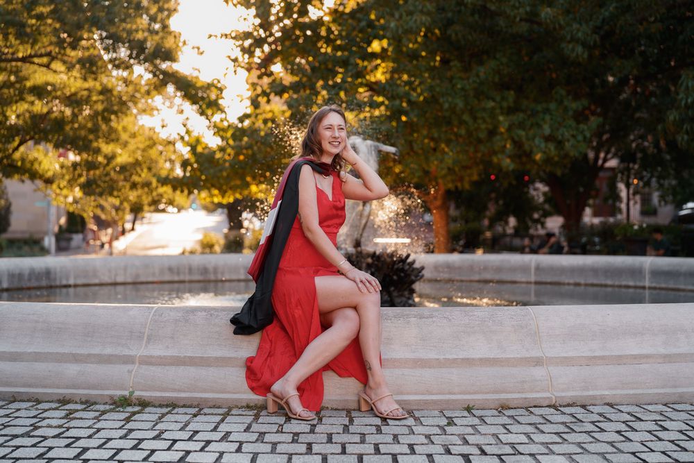A couple in red outfits poses together during a golden hour photoshoot on a stone pathway.