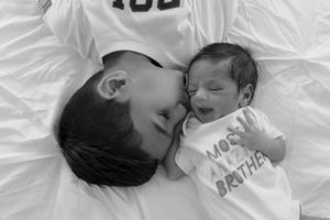 Two people lying on white bedding share an intimate loving moment together in black and white photography.