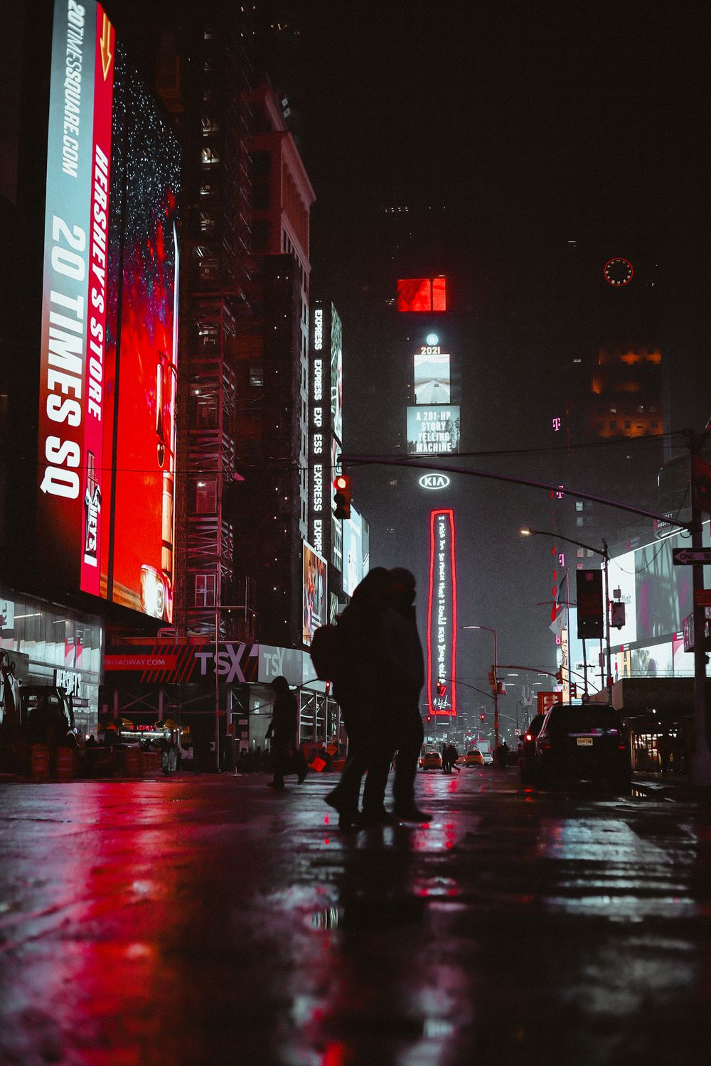 Silhouette against neon Times Square billboards on rainy night.