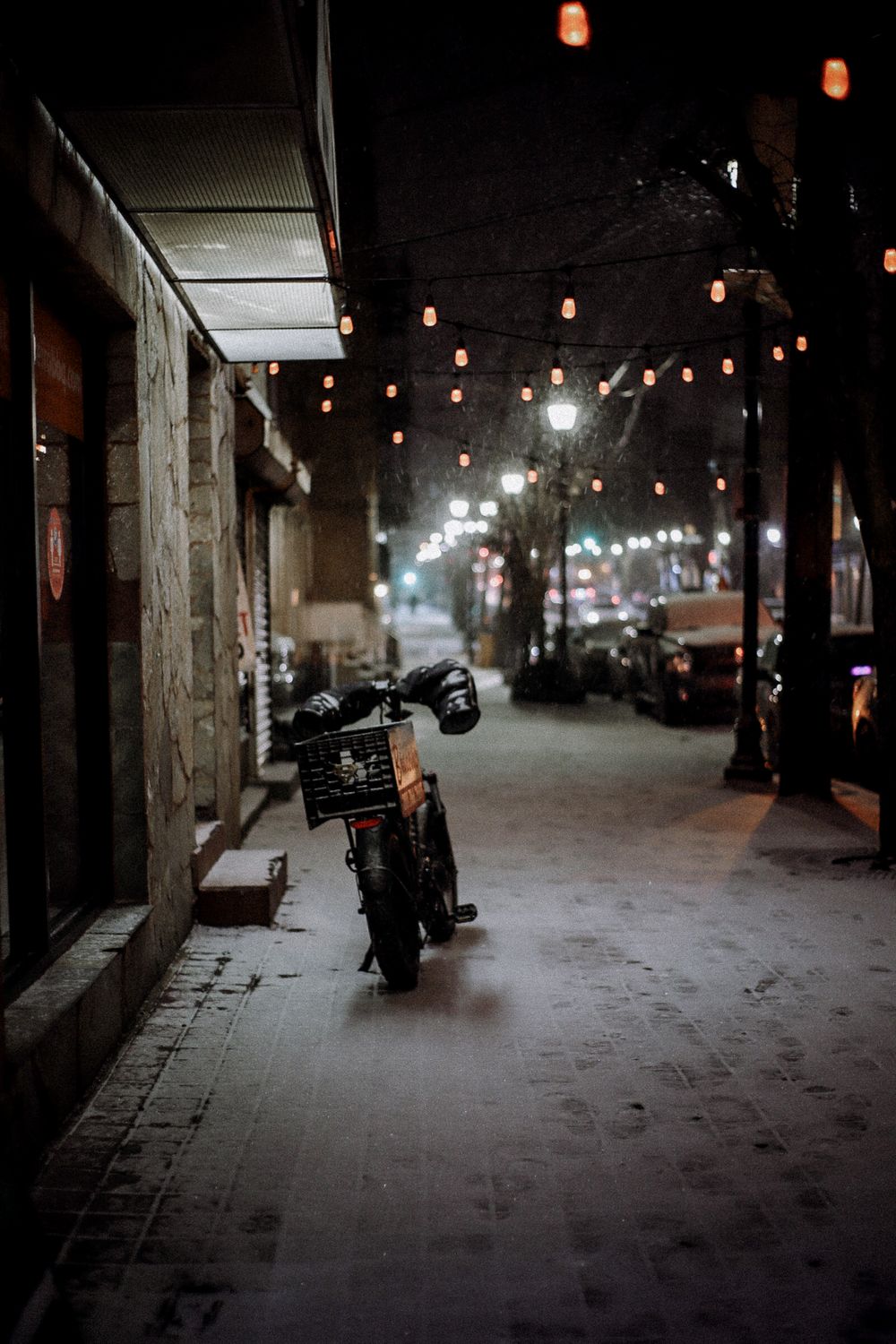 Parked motorcycle in dimly lit alley with string lights overhead.