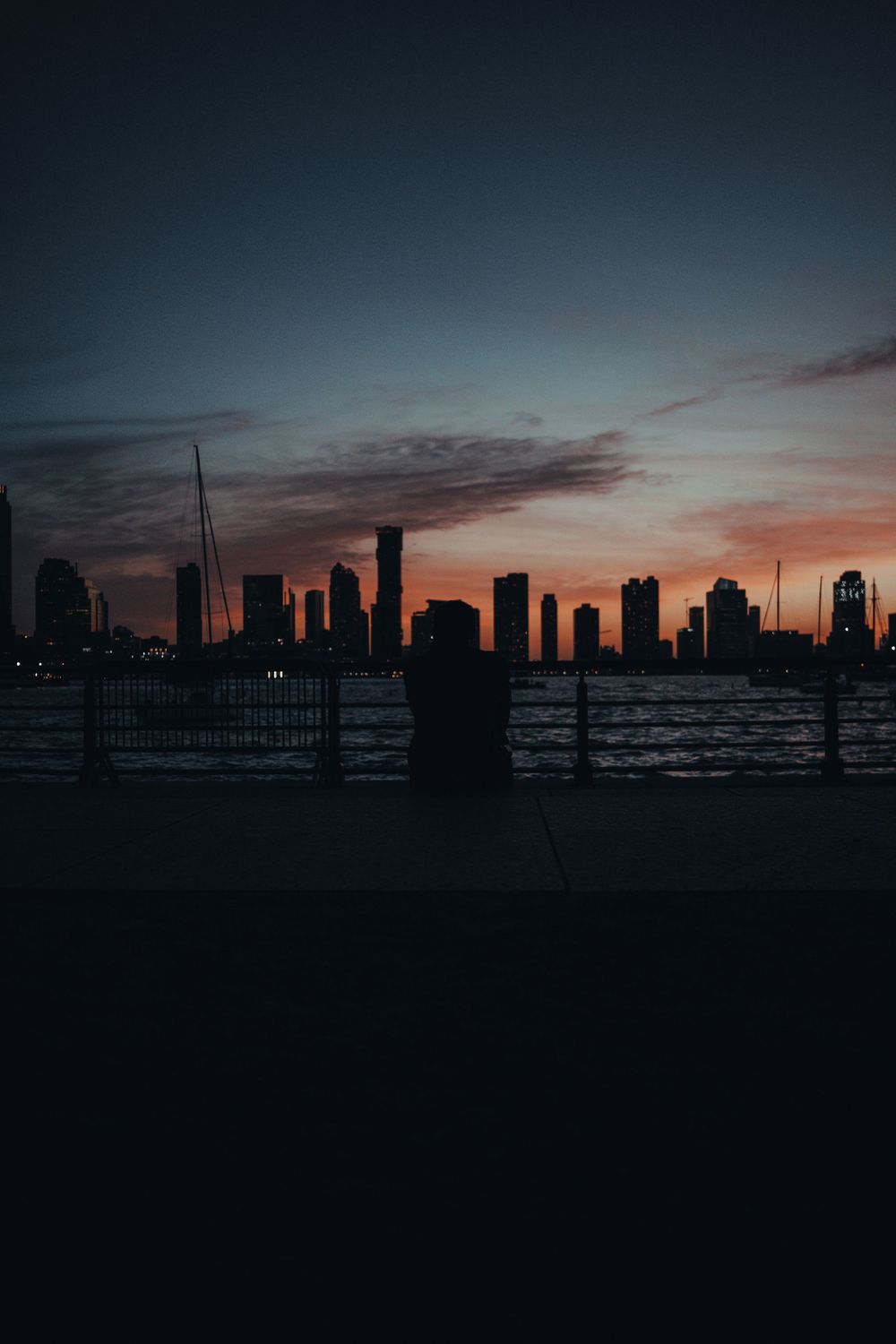 City skyline silhouetted against colorful sunset sky over water.