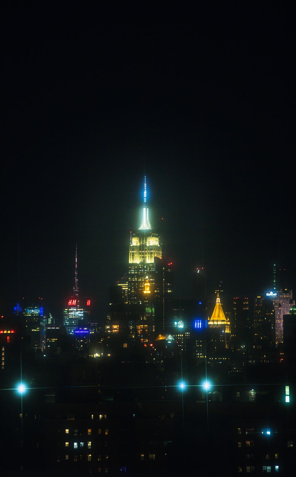 Empire State Building illuminated at night against dark sky with city lights.