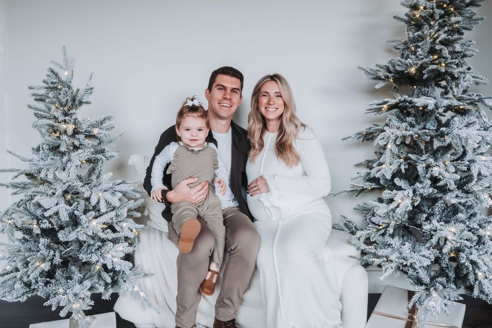 A family of three cuddle together at Christmas.