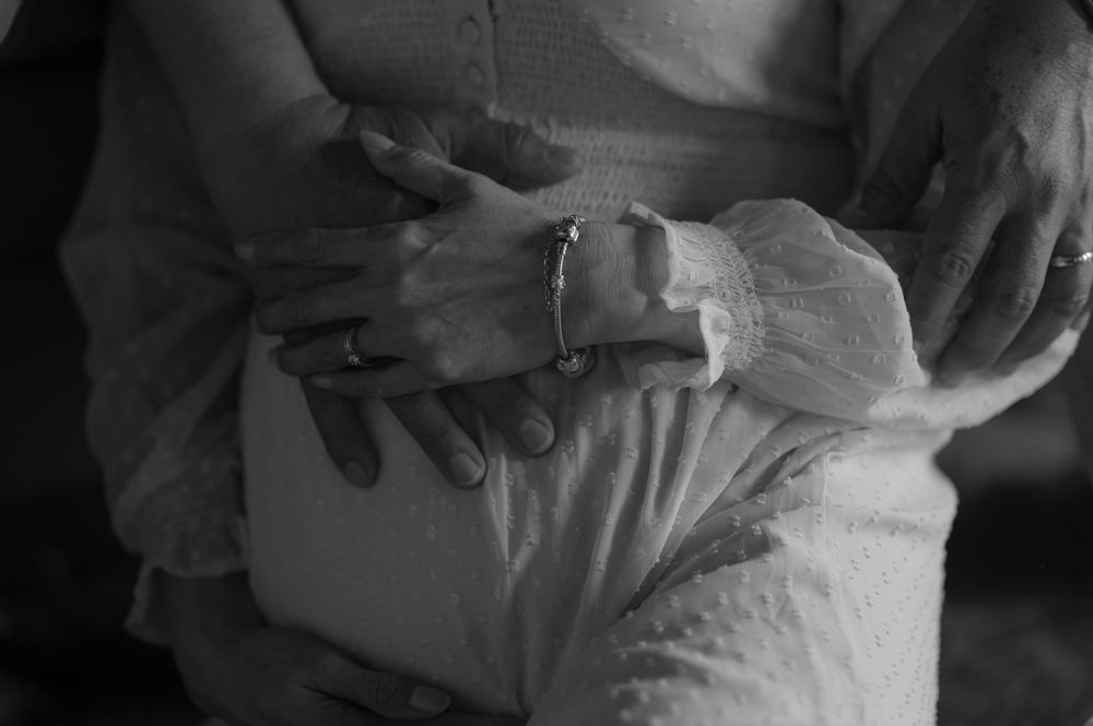 Close-up black and white photo of hands with bandages and medical dressing in a hospital setting.