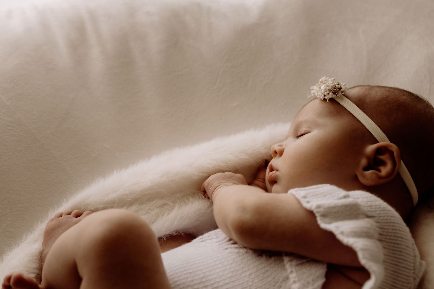 Peaceful resting pose against white bedding in soft, dreamy lighting.