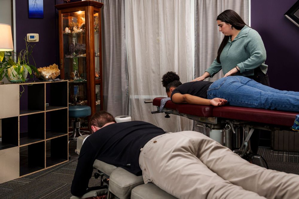 A client receives chiropractic treatment on a medical table in a professional office setting.