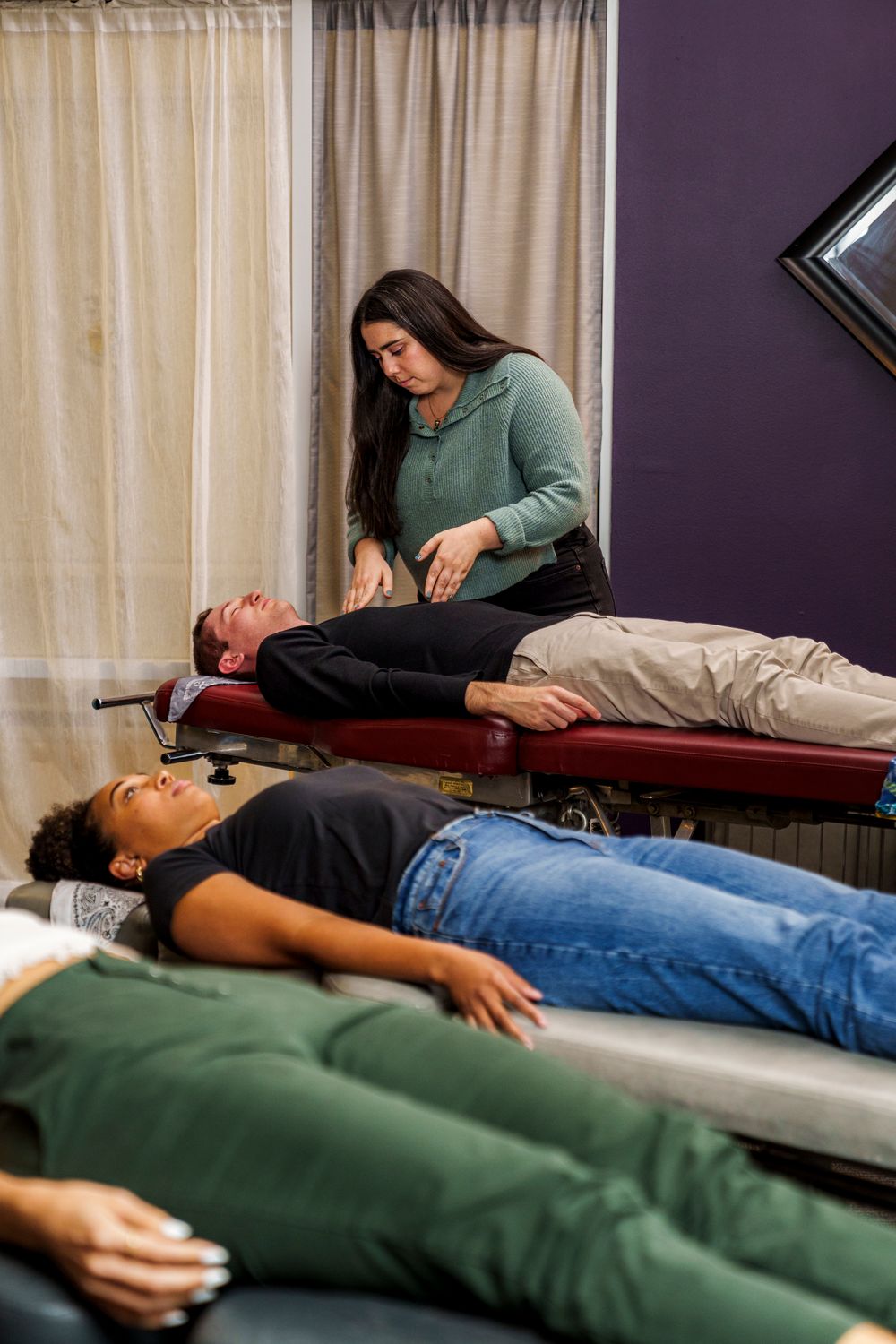 Multiple patients receiving chiropractic adjustments on treatment tables in medical office.
