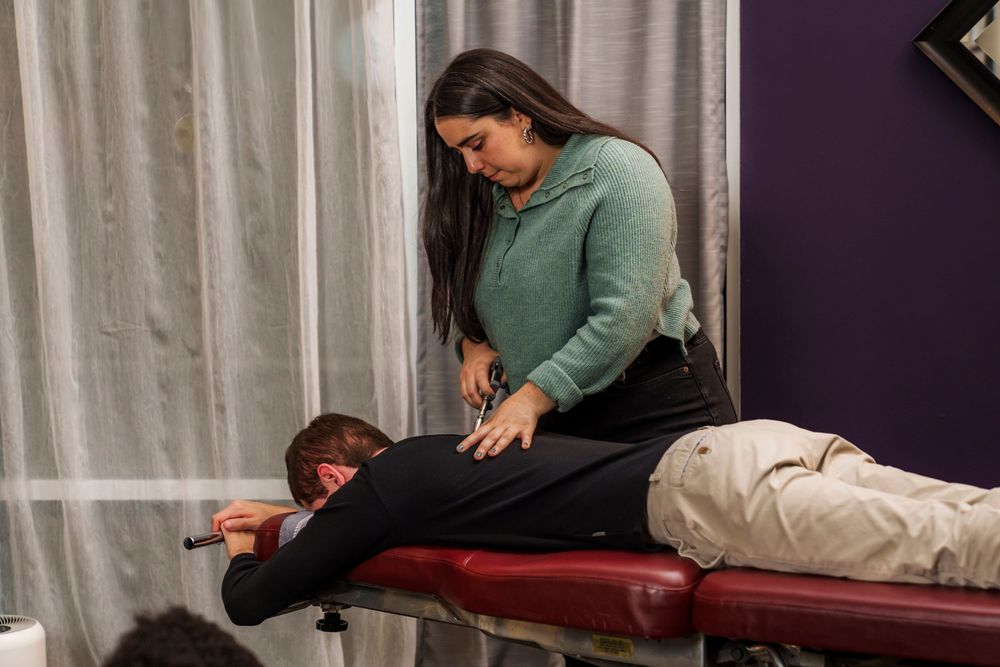 Chiropractor performing spinal adjustment on patient during treatment session.