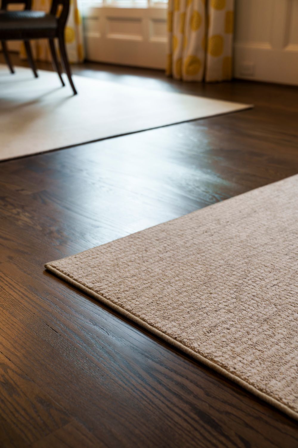 Close-up view of a textured beige carpet meeting dark hardwood flooring in an elegant room.