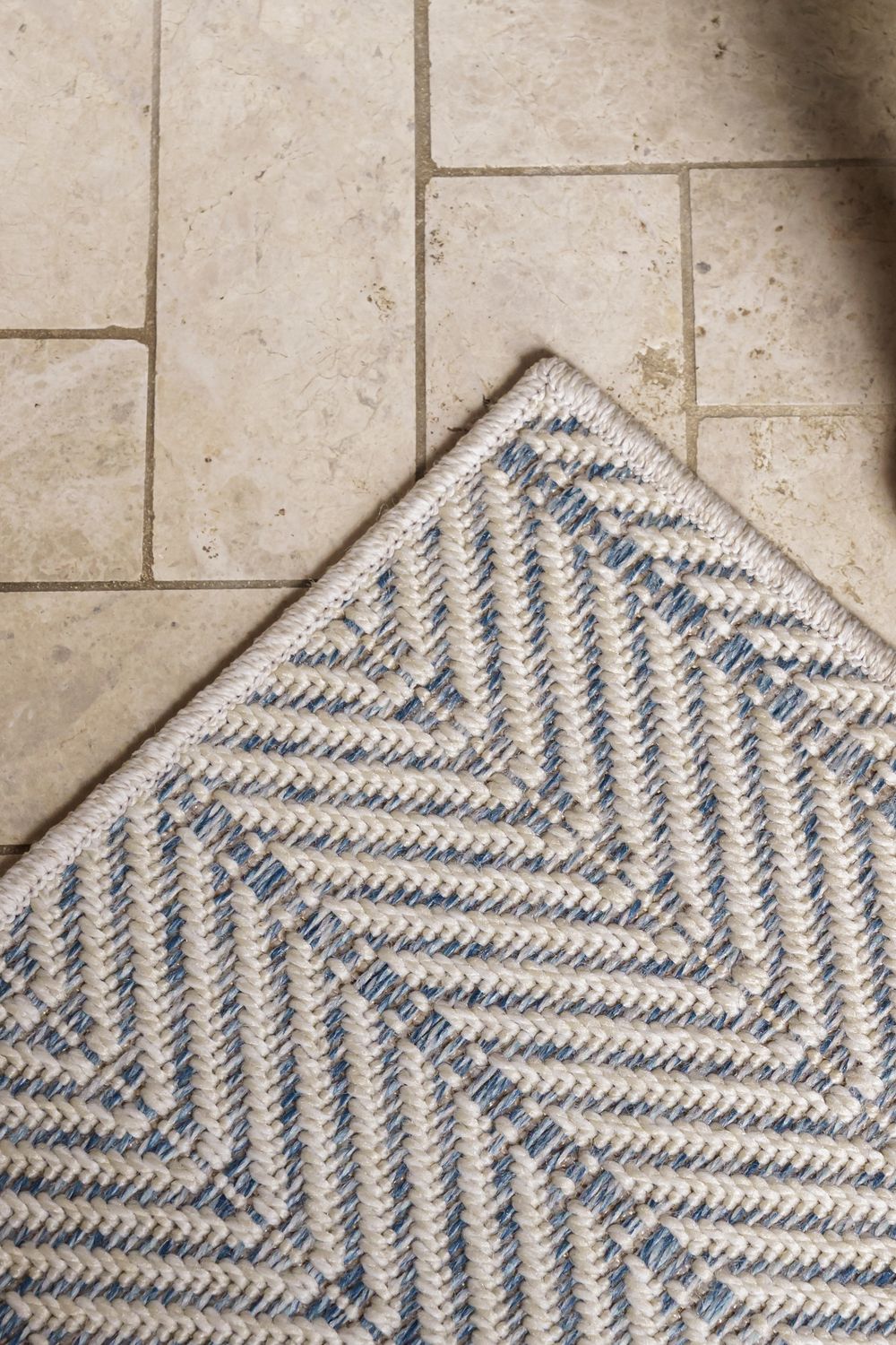 Close-up sequence showing a blue and white chevron patterned rug or carpet unrolling across a tiled floor.