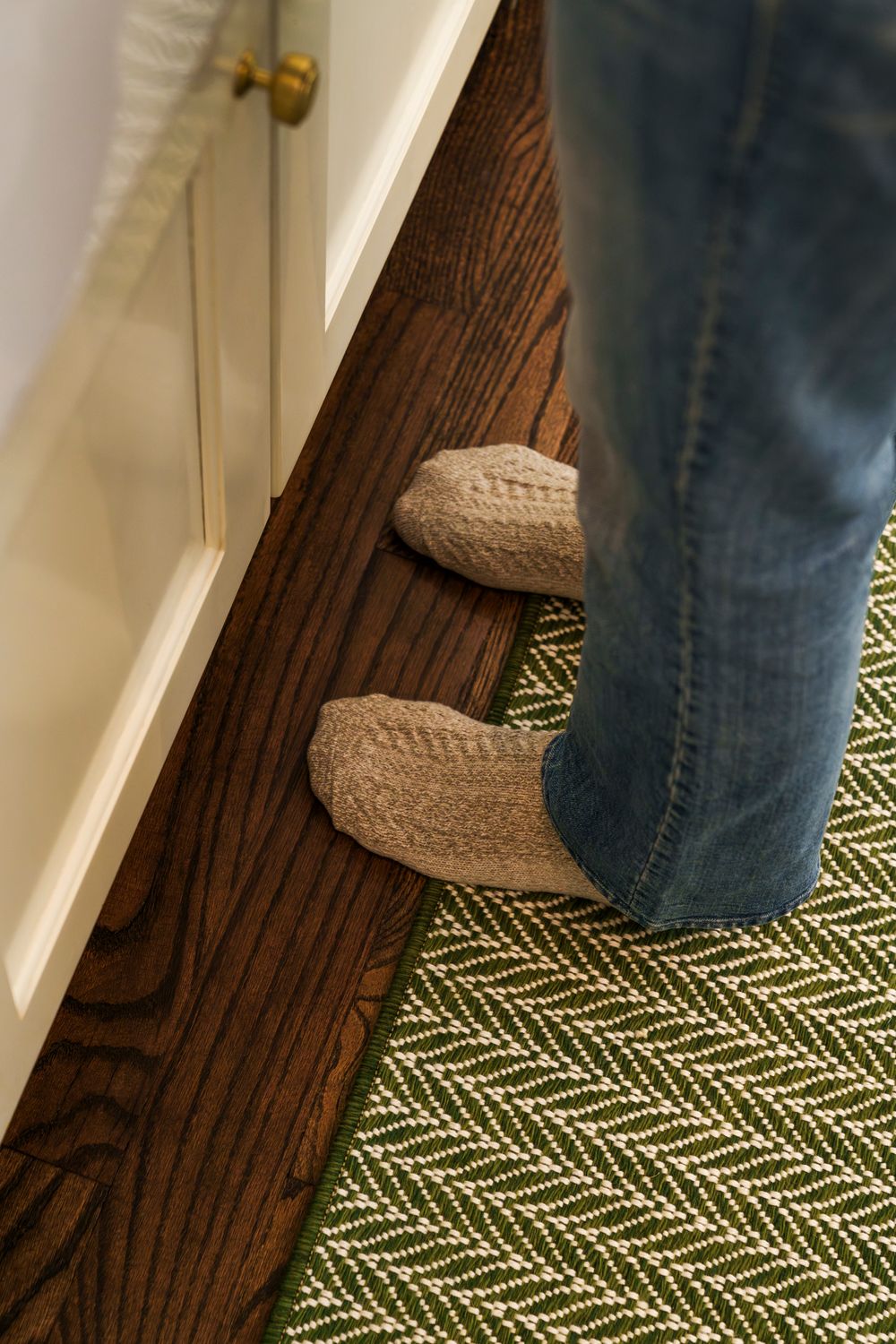 A sequence of footsteps on a patterned green and white carpet next to a dark wooden baseboard.