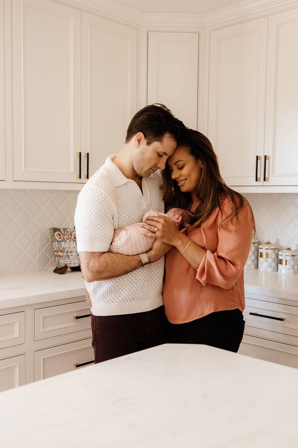 Parents cuddle their new baby in their kitchen in Los Gatos